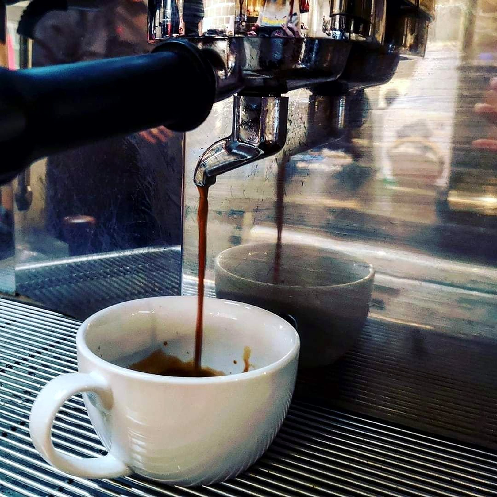 Espresso pouring from the machine into a white cup
